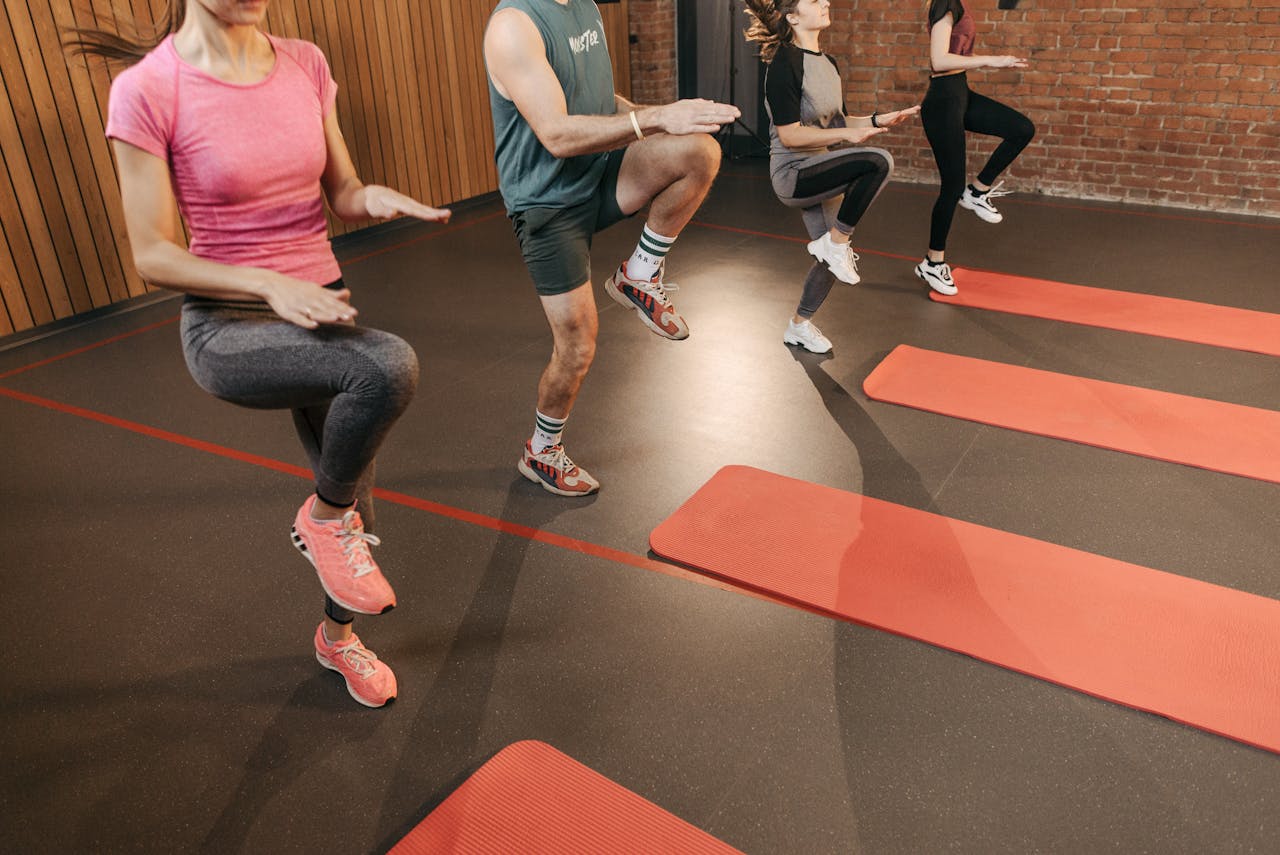 Services A group performs high knees together in an indoor fitness studio with yoga mats.